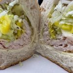 A sandwich with ham, lettuce, and pickles.